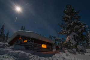 Vintertid i Jokkmokk och fullmåne över timmerkoja på äventyr med hundspann.