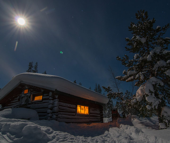Vintertid i Jokkmokk och fullmåne över timmerkoja på äventyr med hundspann.
