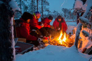 Lunchpaus över öppen eld i skogslandskap på turen Hundspannsäventyr och norrskensnätter vinter lappland.