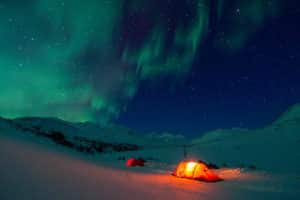 Northern light in Rapadalen Sarek National Park. Red tents and green snow.
