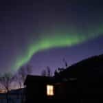 northern lights over a mountain cabin in wintry lapland